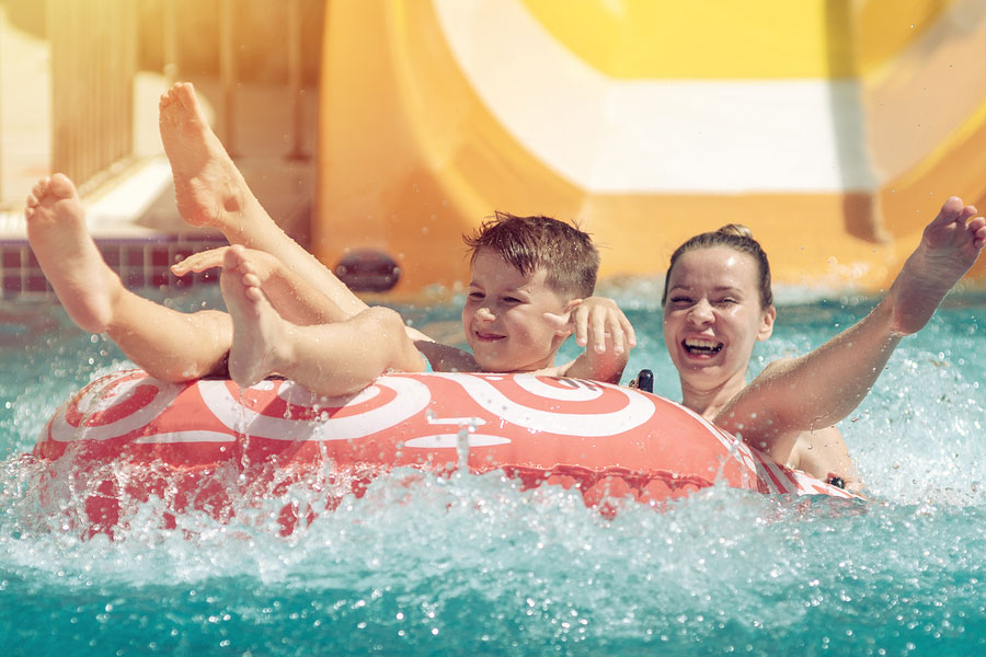 Mother and son having fun on the water slide in a water park
